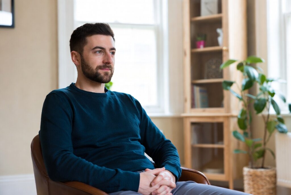 Man sitting in a comfortable therapy room during a mens mental health counselling session in Hampstead