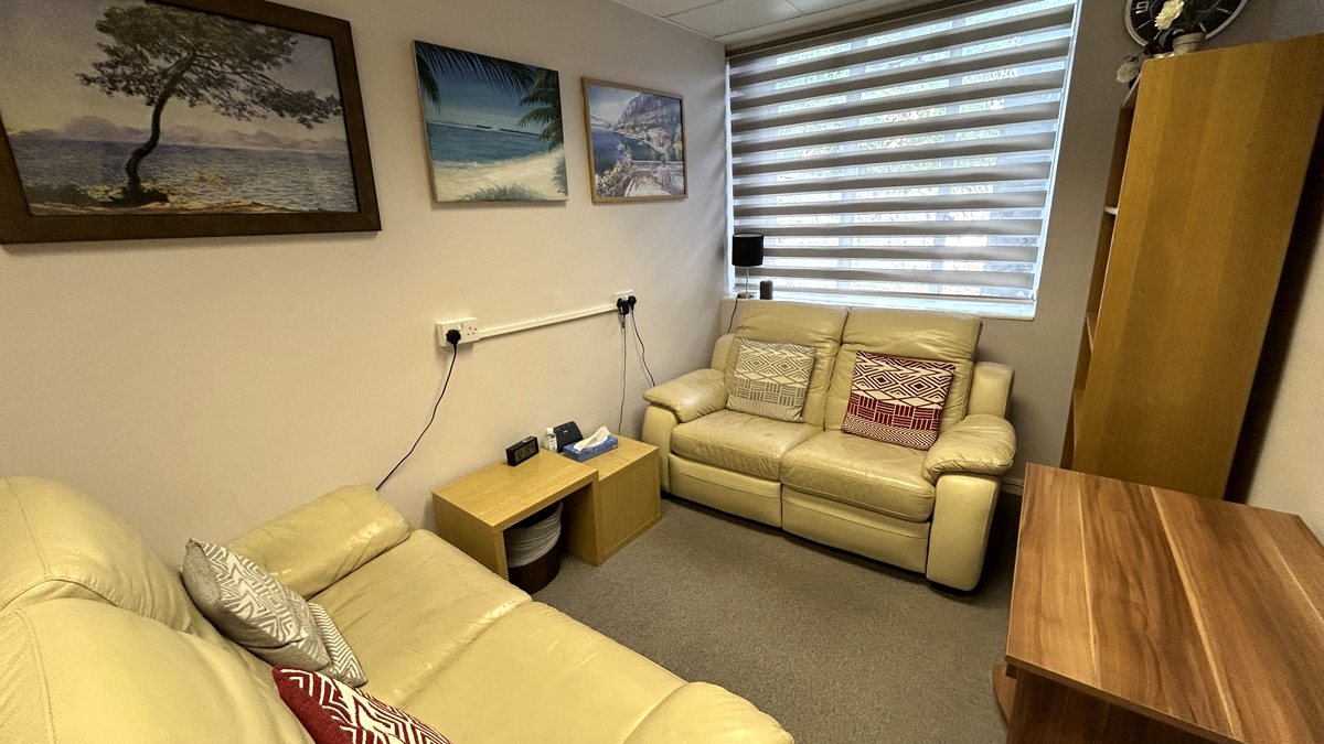Therapy room with two cream sofas and calm seaside paintings